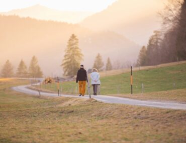 woman in black jacket and white pants walking on road during daytime