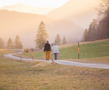 woman in black jacket and white pants walking on road during daytime